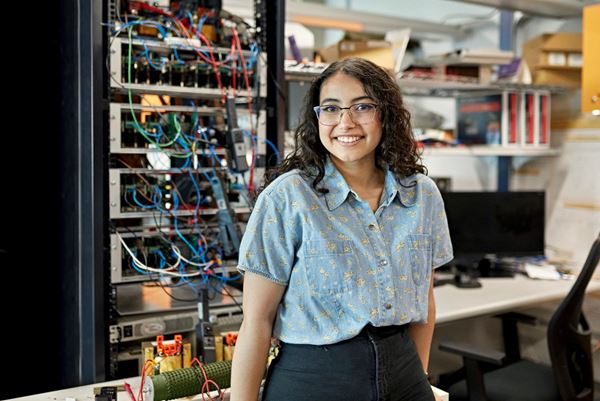 Female lab technician standing in front of a rack of instruments
