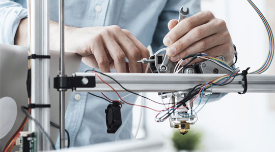 An engineer working on electronics prototype and adjusting tension on a slide arm unit.