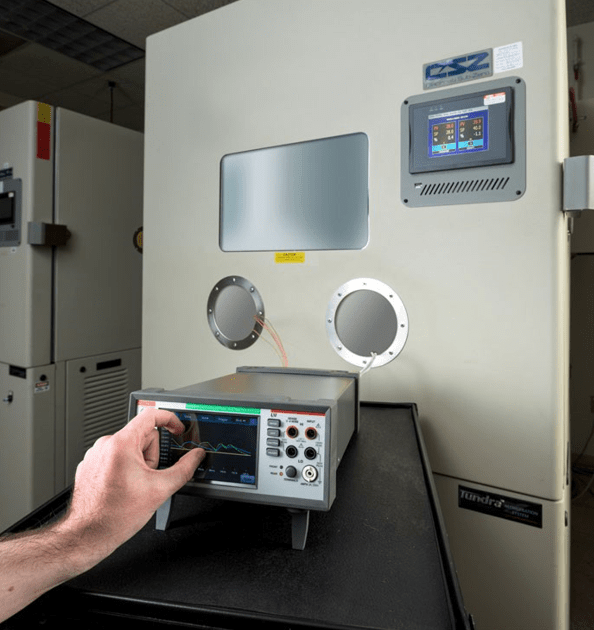 A photo showing a Tektronix DAQ6510 monitoring components inside an environmental test chamber.